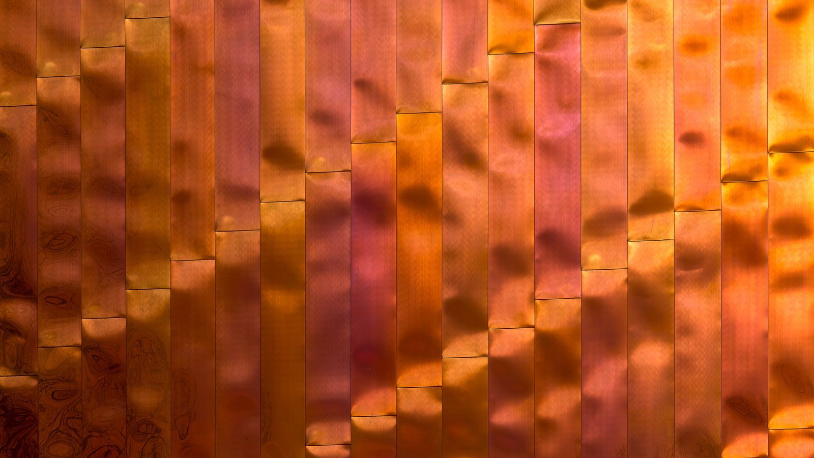 Close-up abstract copper-coloured metallic texture, warm light reflecting