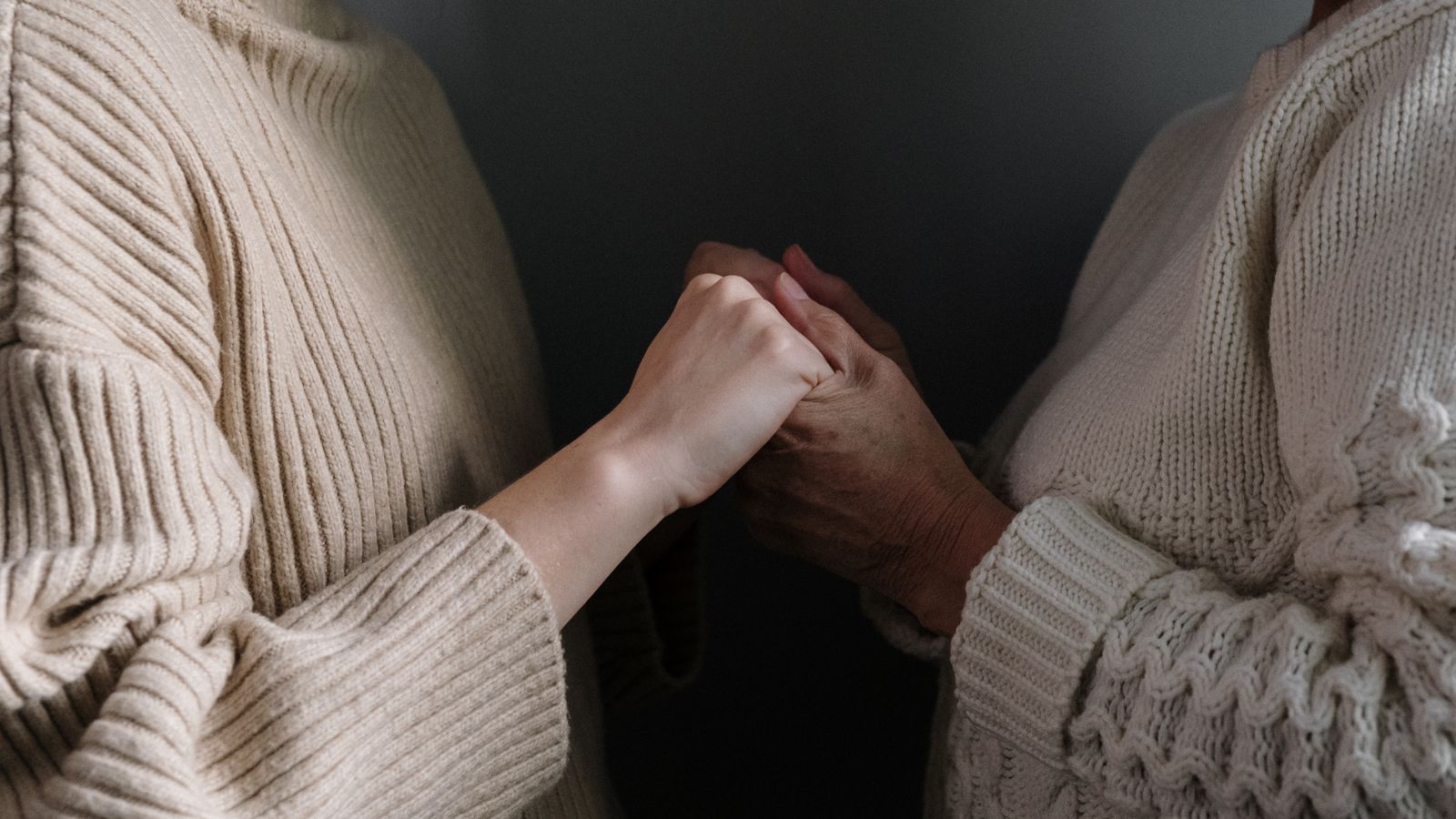 mother and daughter hands together on a soft blanket, warm tones
