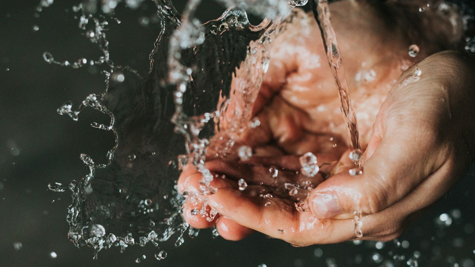 Two cupped hands catching a splash of clear water