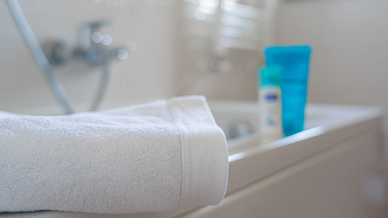 white cotton and soft blue towel on bathroom counter in bright light