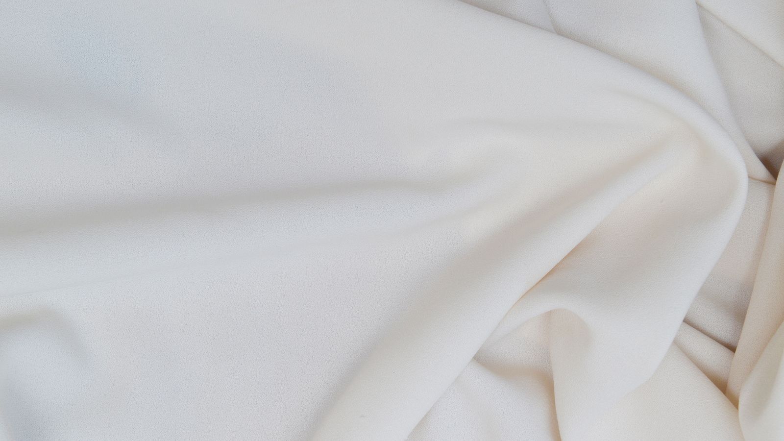 white silk fabric draped in soft natural light on a bed